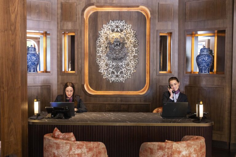 Dos recepcionistas trabajan sentadas en el mostrador de la recepción del hotel.